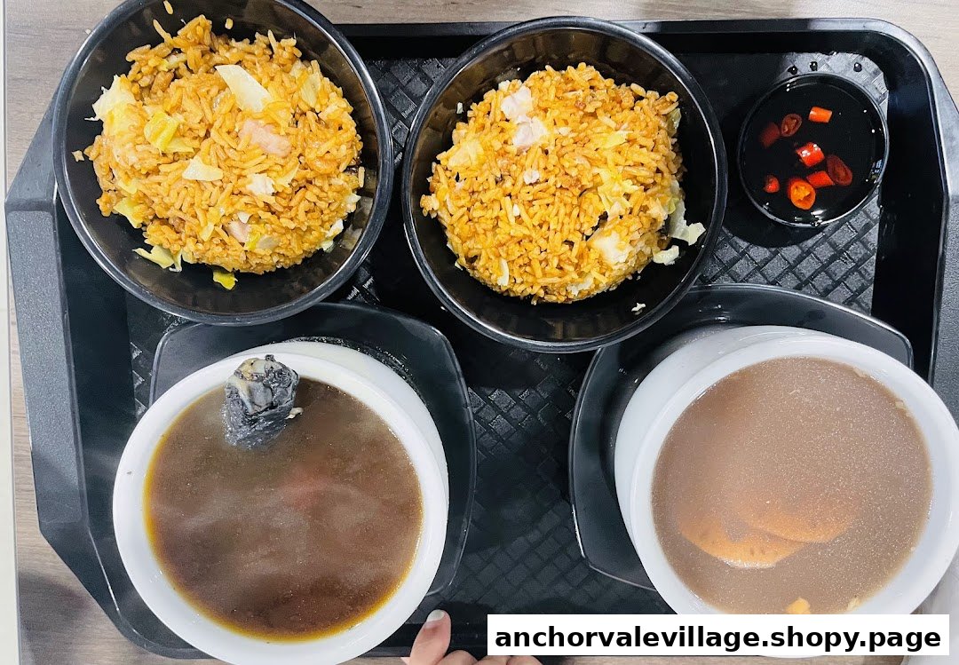 A tray featuring two servings of fried rice, two bowls of traditional Chinese soup, and a chili dipping sauce.