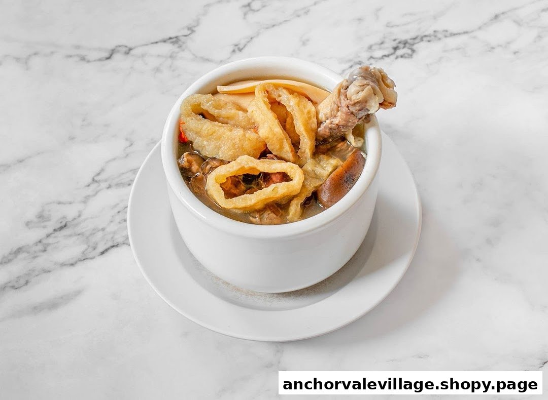 A hearty bowl of traditional Chinese soup with chicken, mushrooms, and other ingredients on a marble surface.