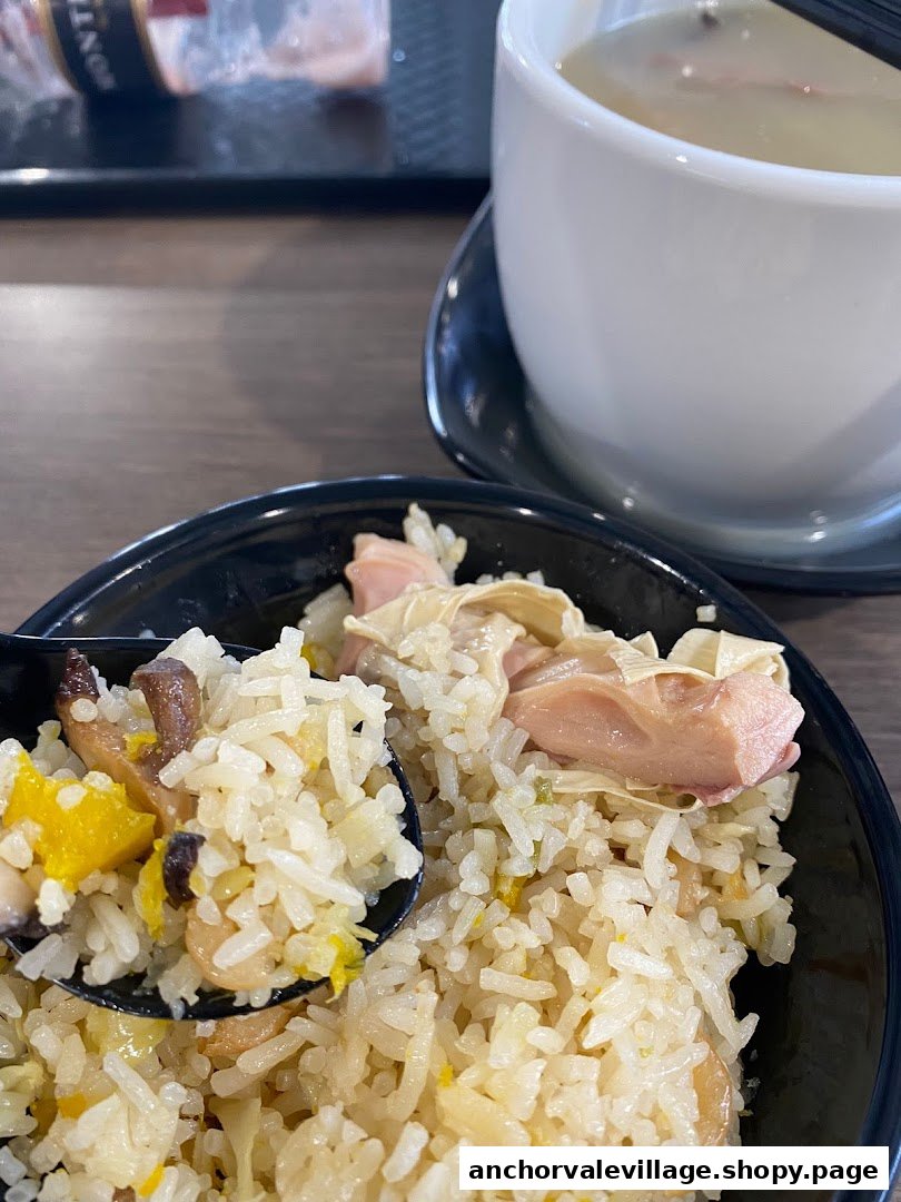 A close-up of flavorful fried rice with various ingredients and a side of comforting soup.