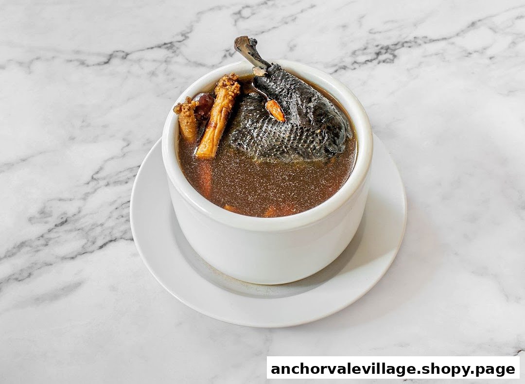 A bowl of traditional black chicken herbal soup with goji berries and other ingredients on a marble surface.