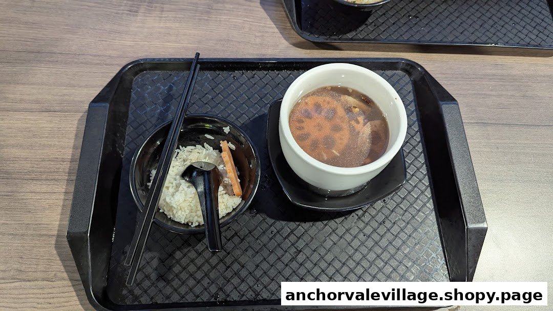 A nourishing meal featuring a bowl of rice and a bowl of lotus root soup on a black tray.