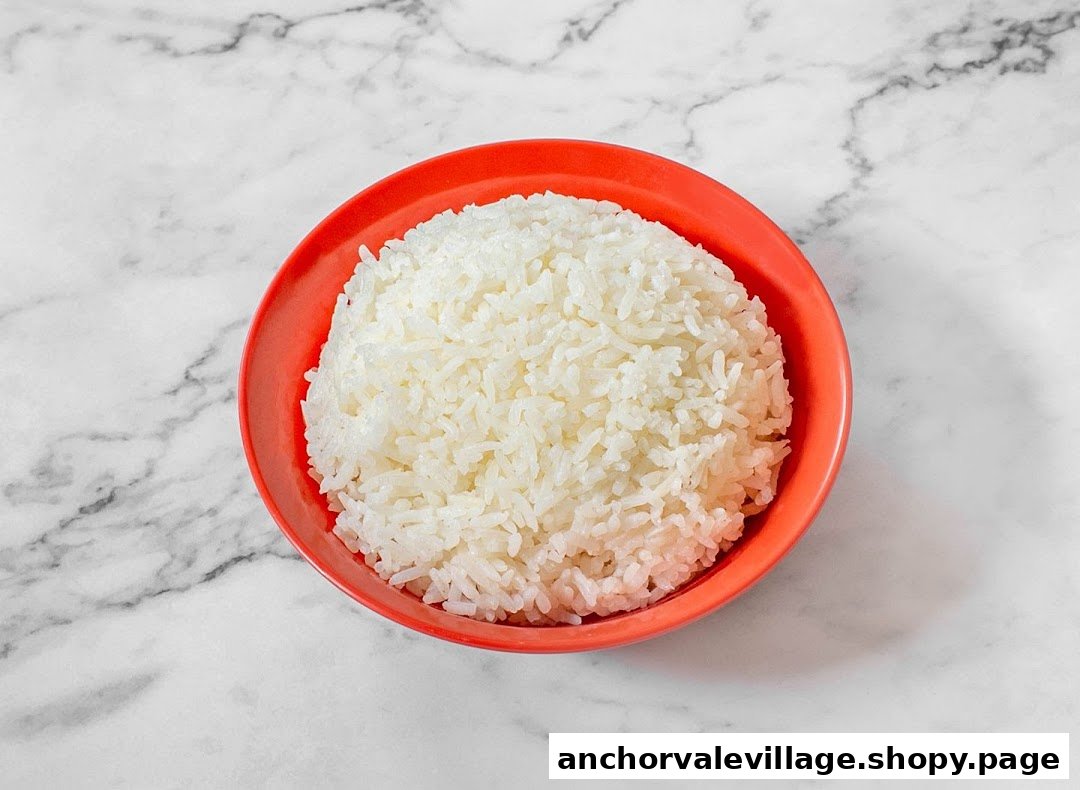 A close-up of a bowl of fluffy white rice in a vibrant red bowl on a marble countertop.