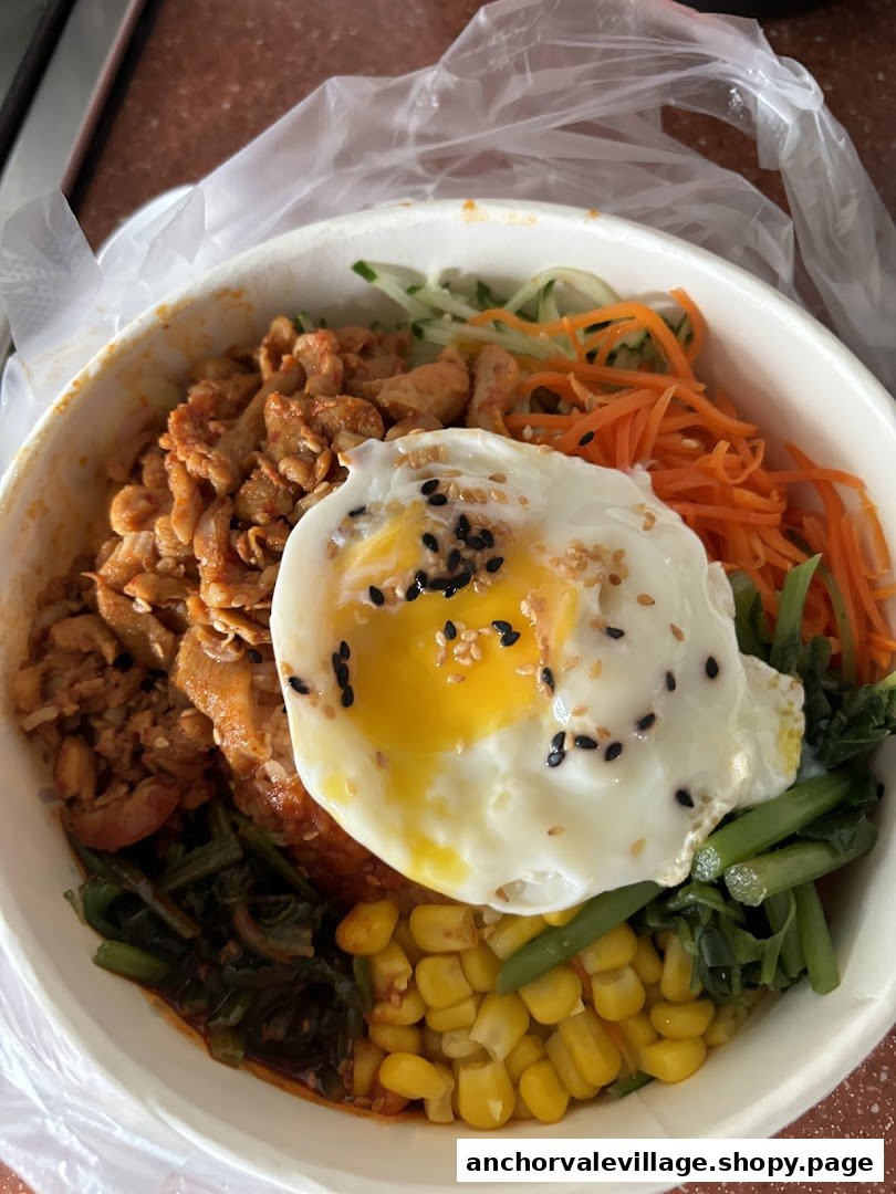 A vibrant bowl of Korean bibimbap with spicy pork, fresh vegetables, and a fried egg.