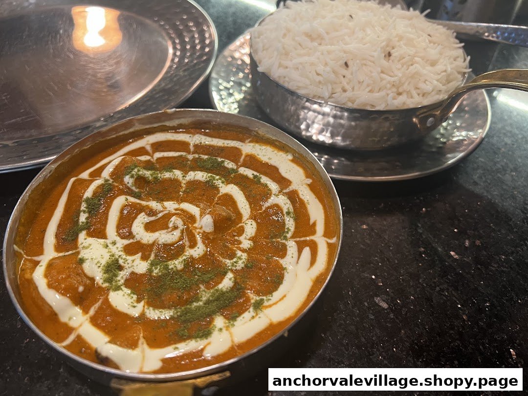 A rich, creamy curry dish garnished with herbs, served alongside a bowl of fragrant basmati rice.