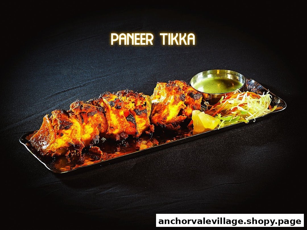 A vibrant plate of Paneer Tikka served with mint chutney, lemon, and fresh salad.