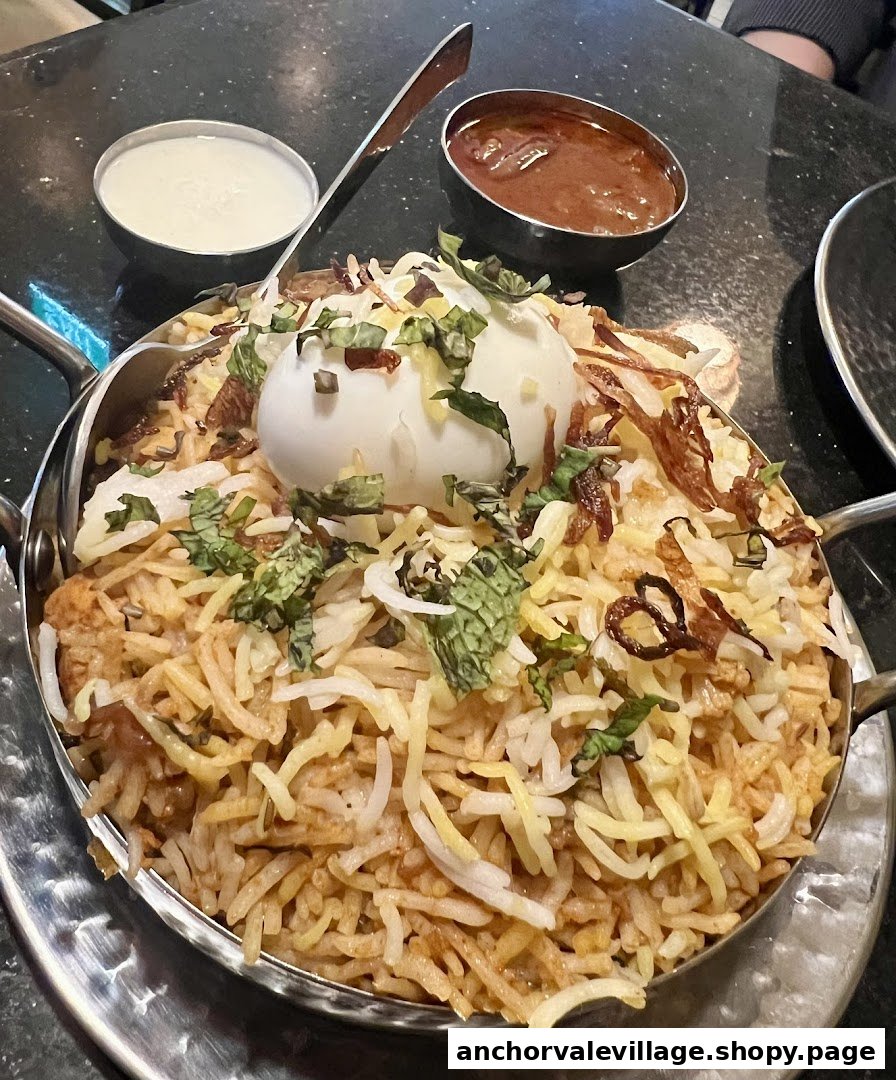 A flavorful biryani dish topped with a boiled egg, served in a traditional pot with accompanying sauces.