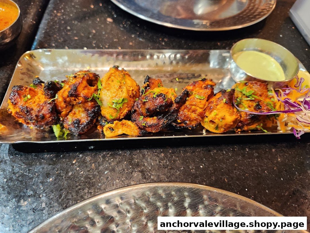 A close-up of a delicious platter of grilled chicken tikka pieces with a side of green chutney and salad.