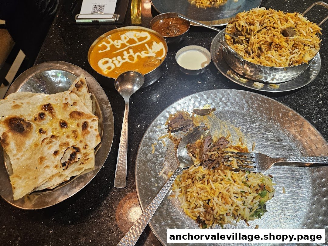 A table laden with delicious Indian dishes including biryani, naan, and a special birthday curry.