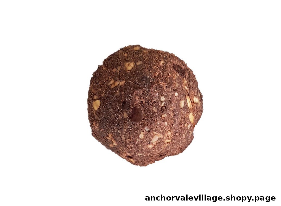 A close-up of a dark brown energy ball with visible nuts and seeds on a white background.