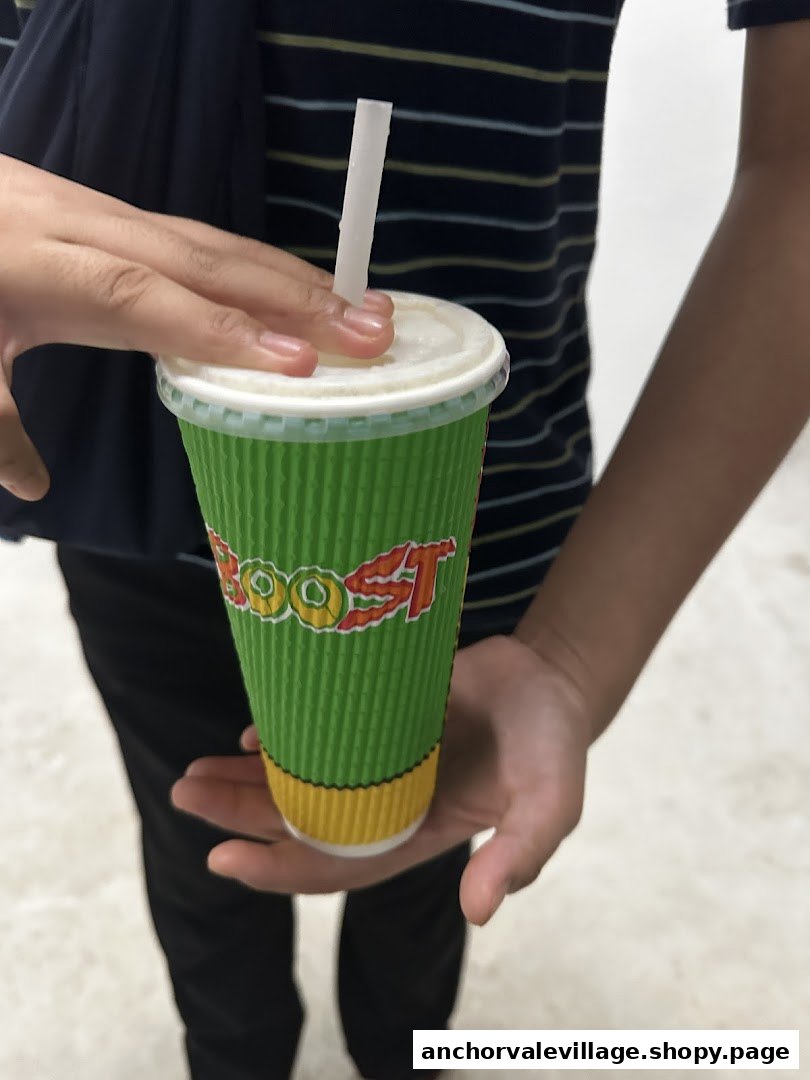 A person holds a vibrant green Boost Juice cup with a straw, ready to enjoy.