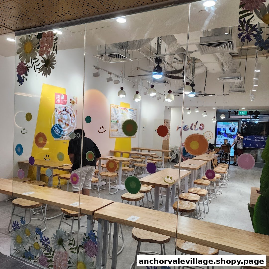 A vibrant and cheerful cafe interior with wooden tables and stools, seen through a glass storefront.