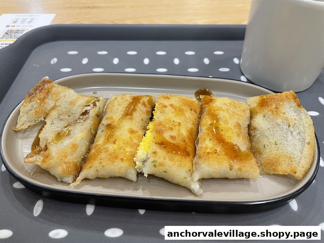 A plate of golden-brown savory pancakes or wraps, cut into pieces and drizzled with sauce.