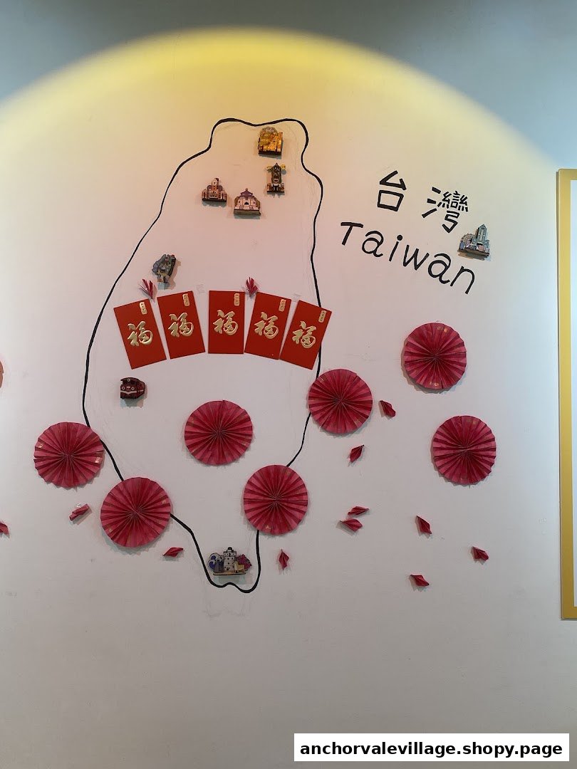A wall decorated with a map of Taiwan, traditional red envelopes, and festive paper fans.