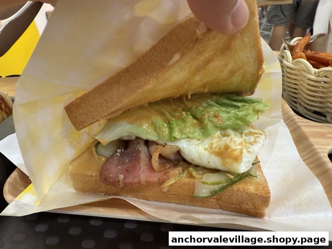 A close-up of a delicious breakfast sandwich with egg, bacon, lettuce, and sauce on toasted bread.