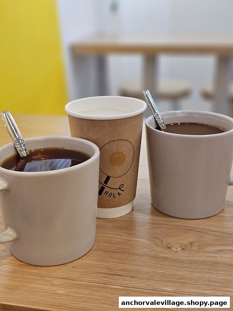 Three beverages, including coffee and water, on a wooden table inside the shop.