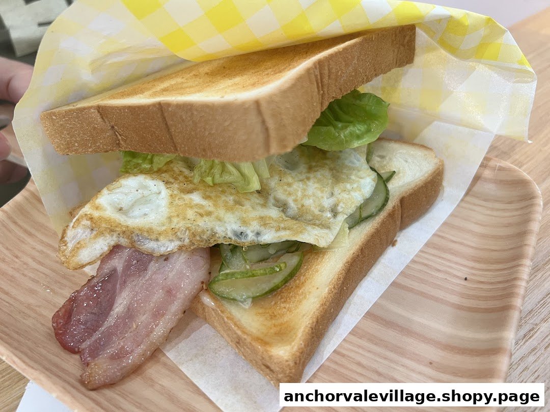 A delicious breakfast sandwich with bacon, fried egg, lettuce, and cucumber, served on toast.