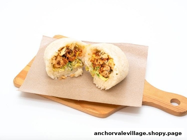 A large rice ball, cut in half, revealing a savory filling, presented on a wooden board.