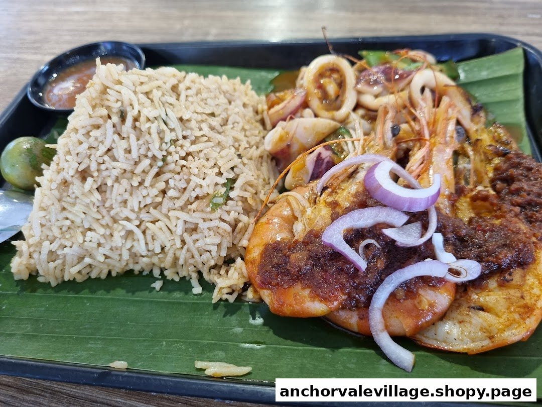 A vibrant dish featuring flavorful rice, grilled prawns, and squid served on a banana leaf.