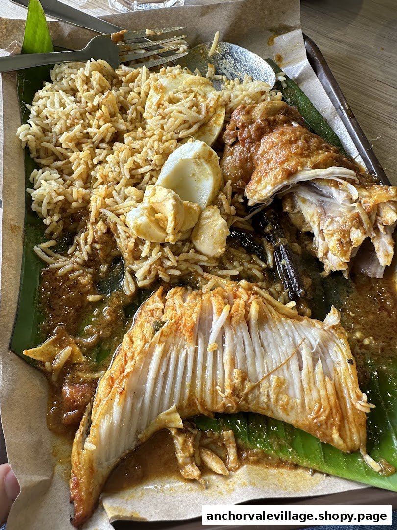 A delicious plate of biryani with chicken, fish, and egg, served on a banana leaf.