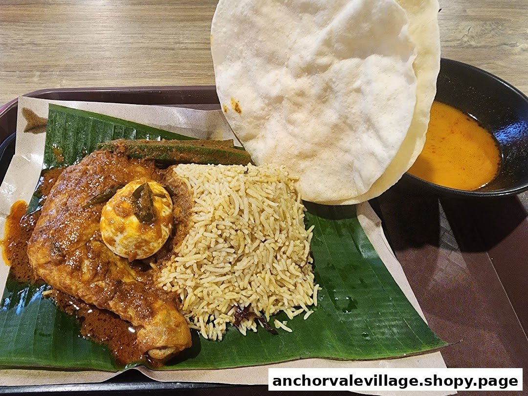 A delicious plate of chicken biryani with egg, okra, and papadum served on a banana leaf.