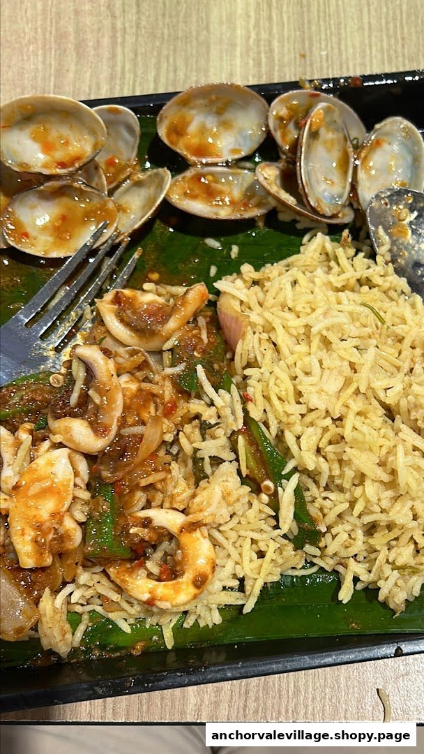 A close-up of a delicious seafood and rice dish, featuring clams, squid, and flavorful biryani.