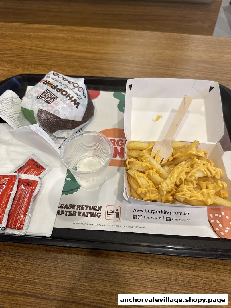 A Burger King meal featuring a Whopper, cheesy fries, and a drink on a tray.