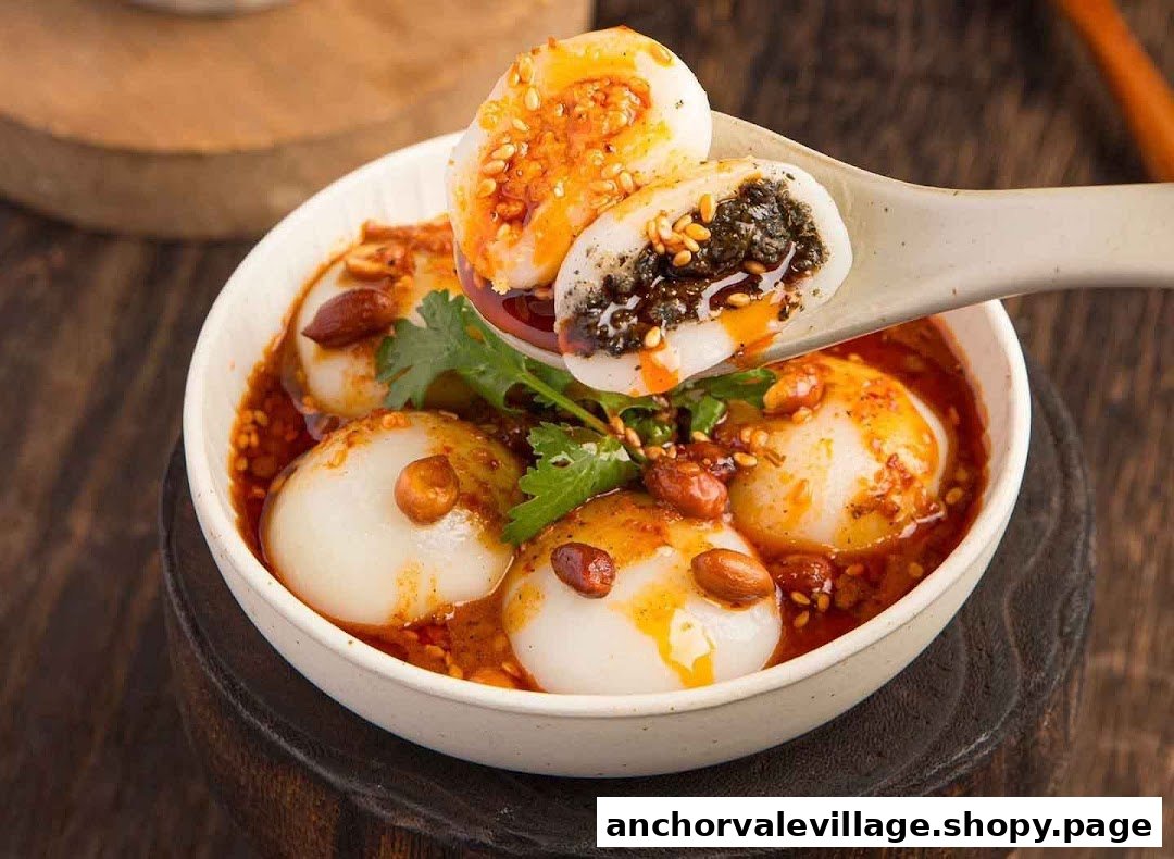 A close-up of savory tangyuan or mochi dumplings with spicy sauce, peanuts, and cilantro.