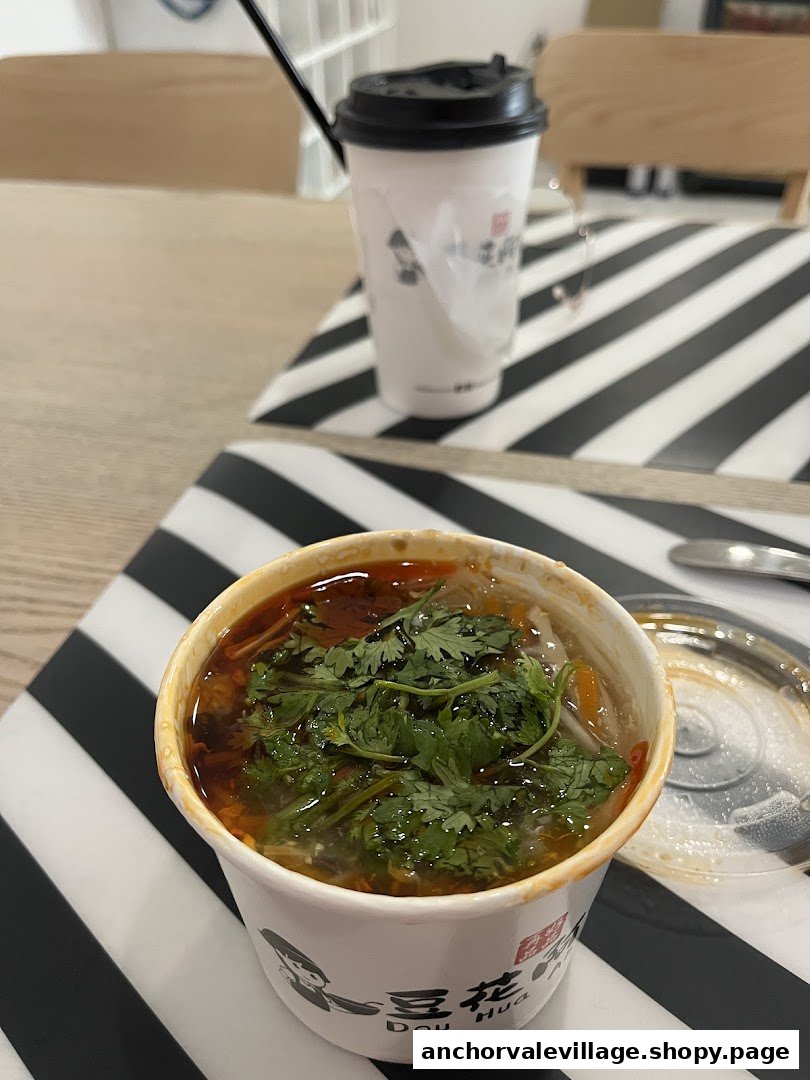A close-up of a savory dish with cilantro and a branded drink cup on a striped table.