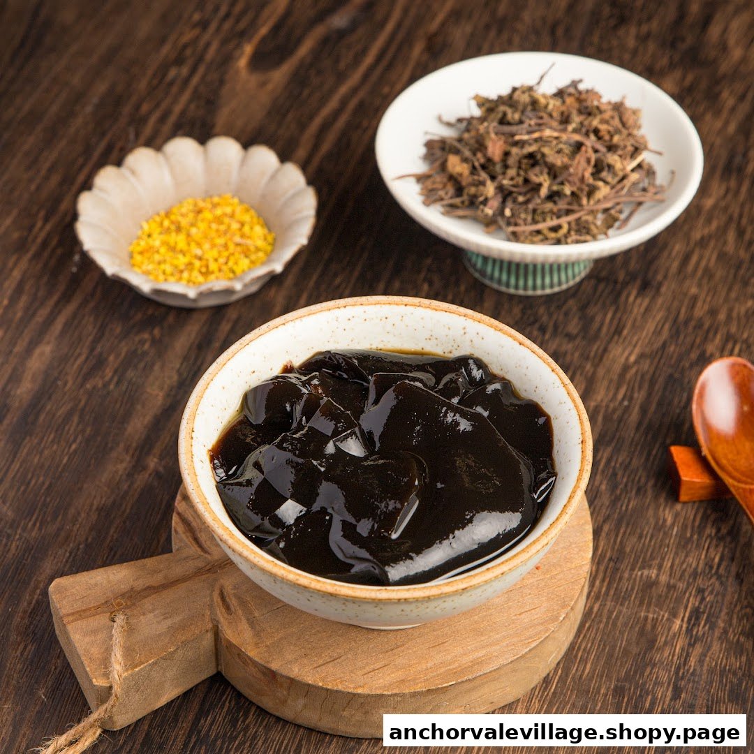 A bowl of dark herbal jelly dessert with dried herbs and yellow granules on a wooden surface.