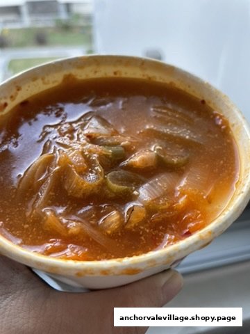 Close-up of a vibrant, spicy soup or stew with onions and vegetables in a bowl.