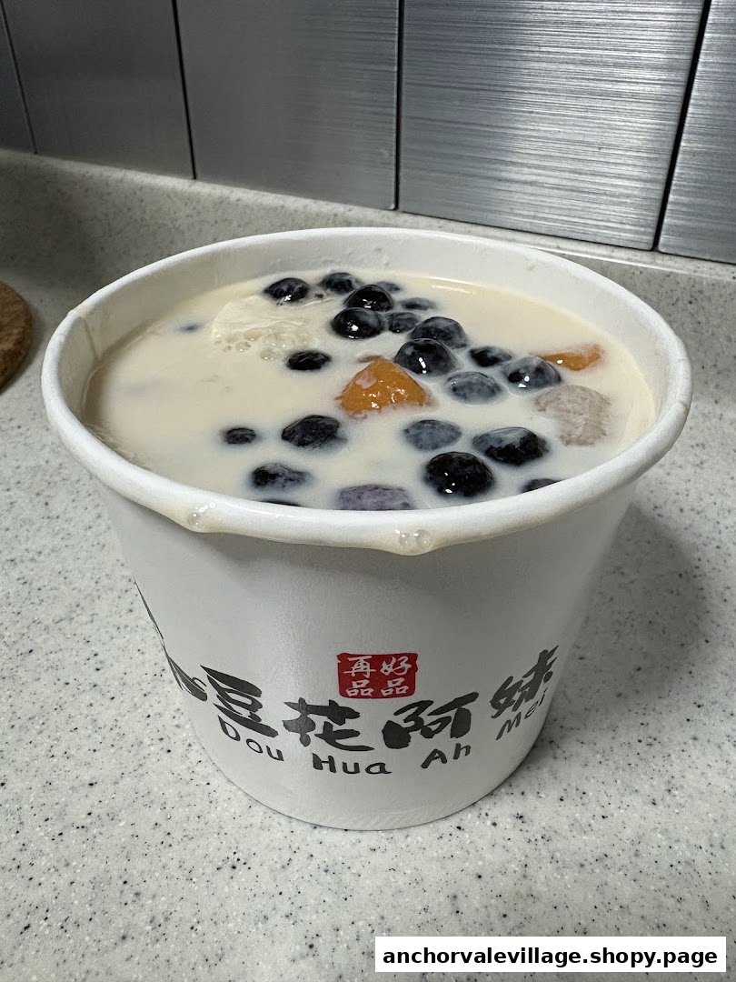 A close-up of a Dou Hua Ah Mei dessert cup filled with tofu pudding and various toppings.