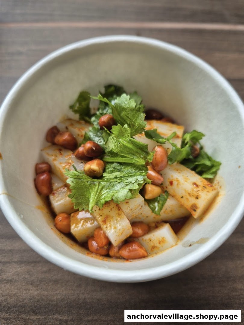 A close-up of a savory dish featuring white rectangular pieces, peanuts, and fresh cilantro in a flavorful sauce.