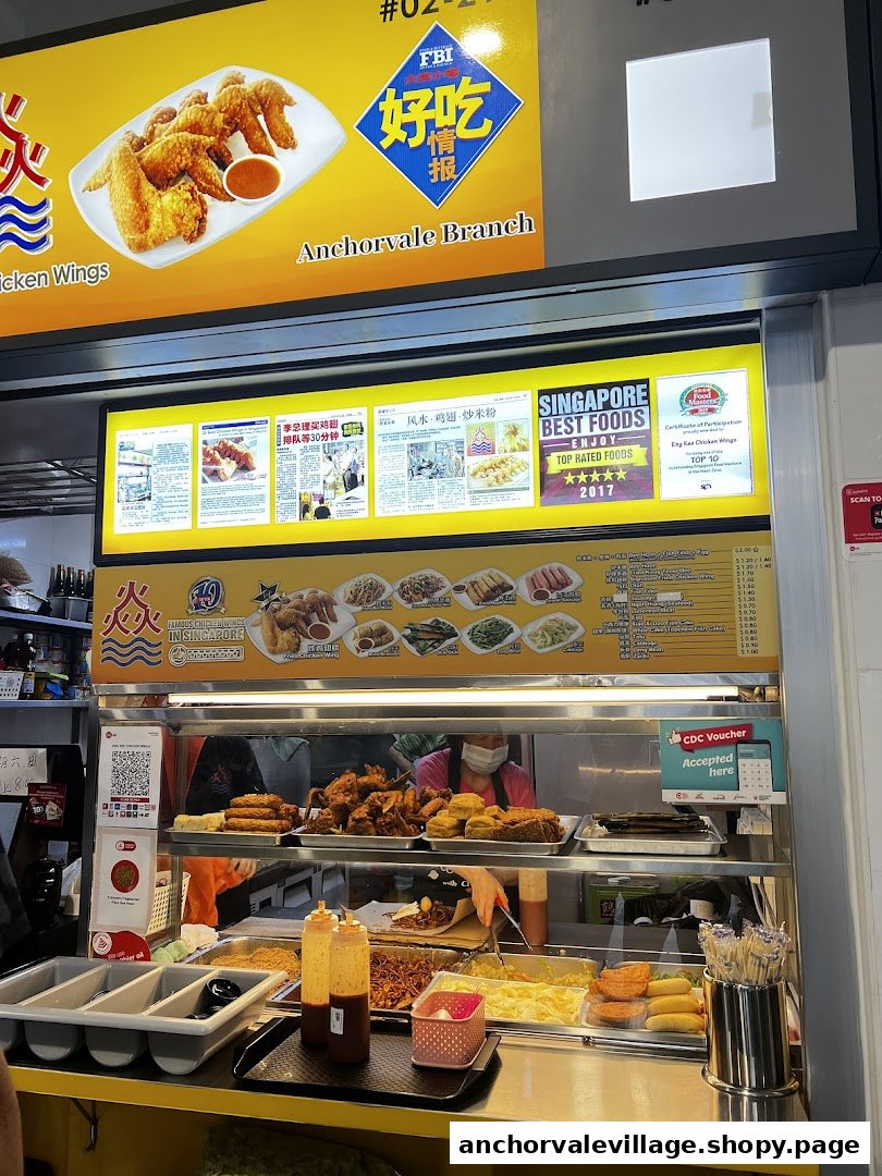 A food stall counter displaying fried chicken wings, various side dishes, and a detailed menu board with prices.