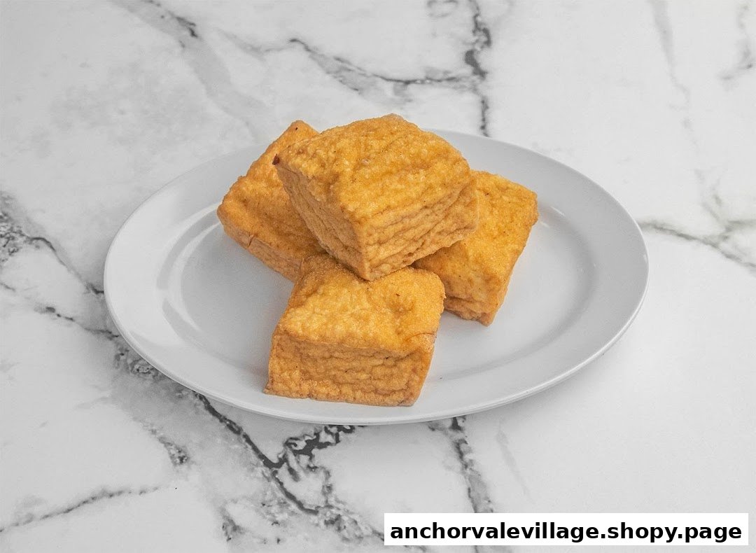 A plate of golden-brown fried tofu squares on a white plate against a marble background.