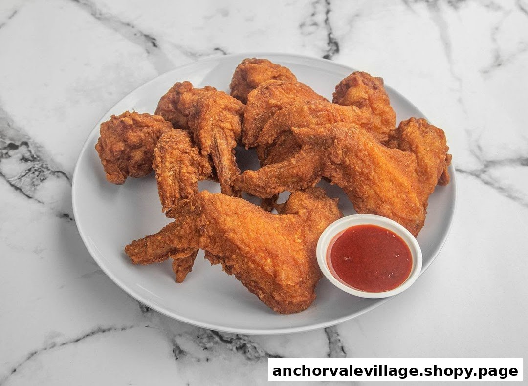A plate of golden-brown crispy fried chicken wings served with a side of red chili sauce.