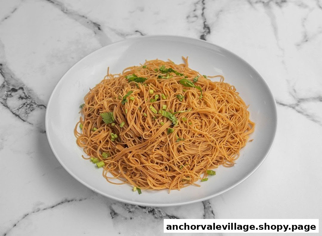 A close-up of a plate of stir-fried vermicelli (bee hoon) garnished with fresh herbs.