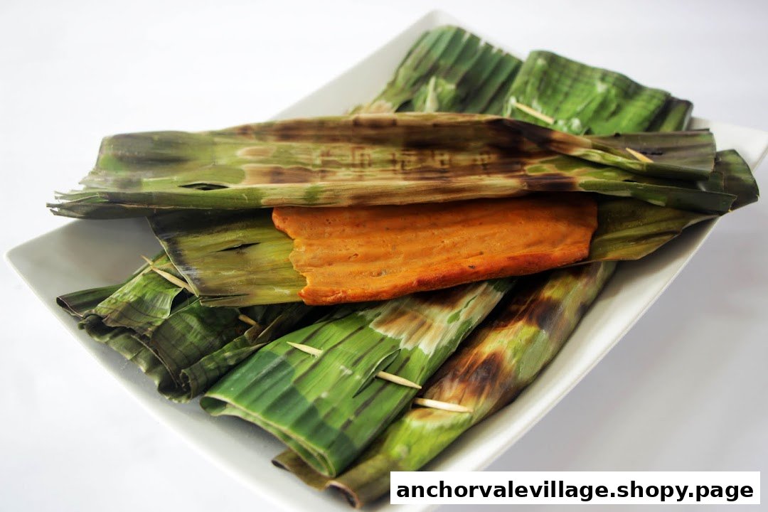A plate of grilled otah (spicy fish paste) wrapped in banana leaves, with one unwrapped.