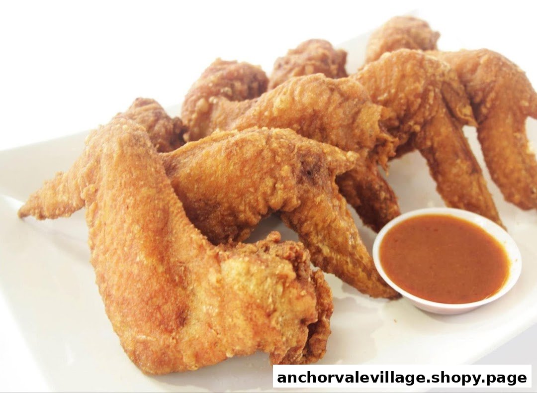 A plate of golden-brown fried chicken wings with a side of dipping sauce.