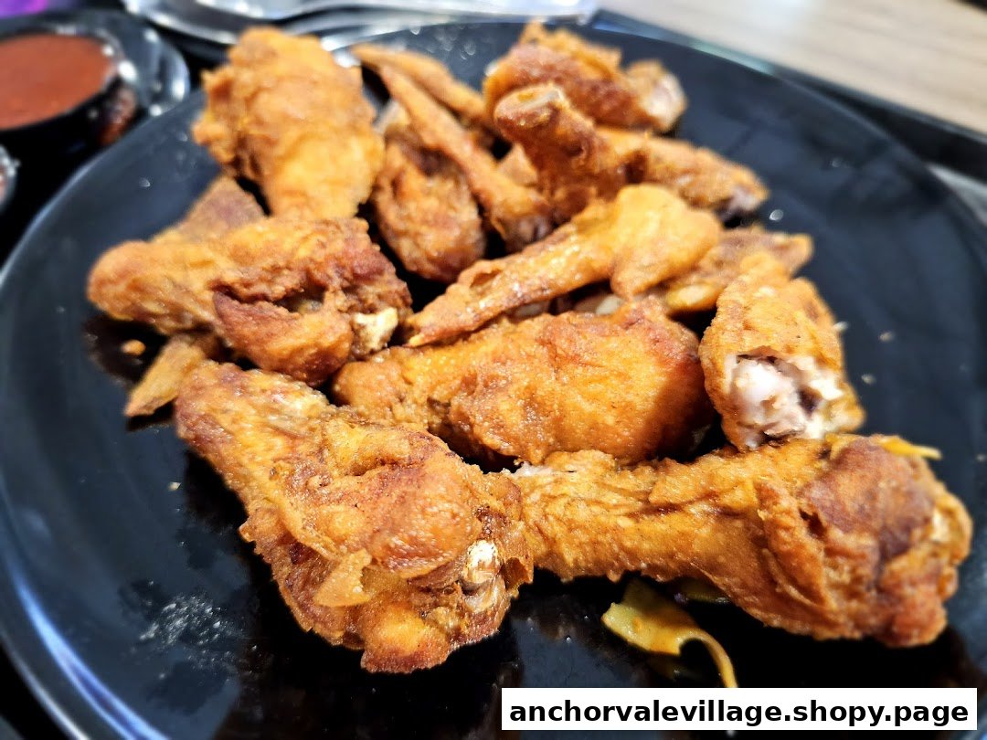 A close-up of a black plate filled with crispy, golden-brown fried chicken wings.