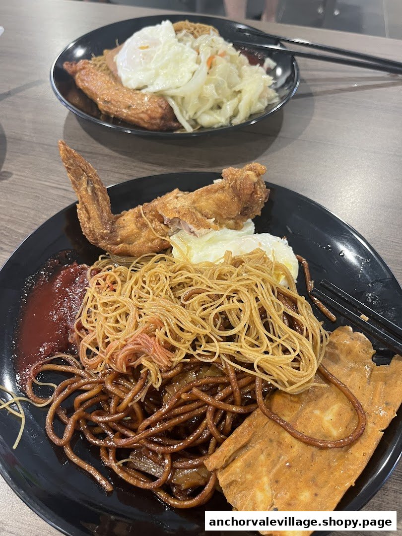 Two plates of delicious fried chicken wings with noodles, fried egg, and other sides.