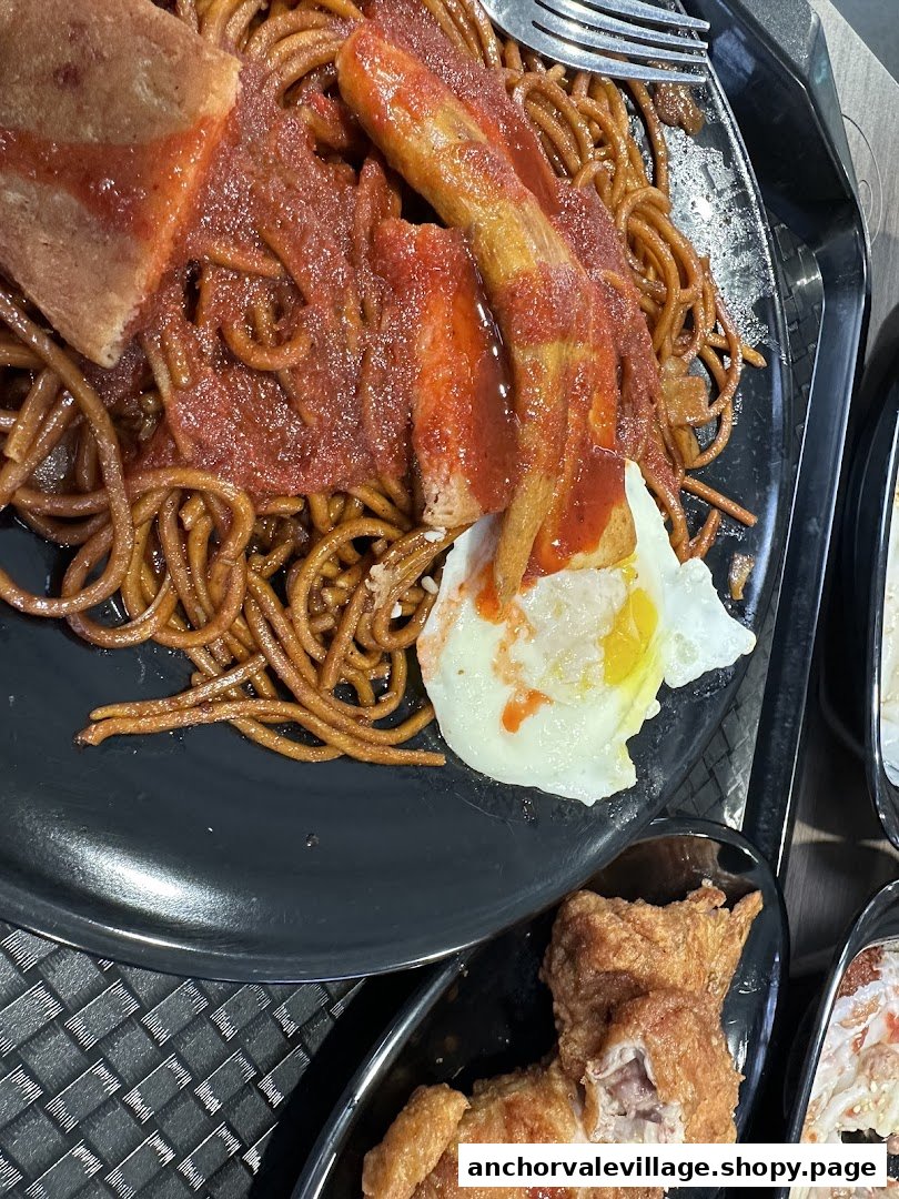 A plate of fried noodles with sauce, fried egg, and a side of crispy fried chicken.