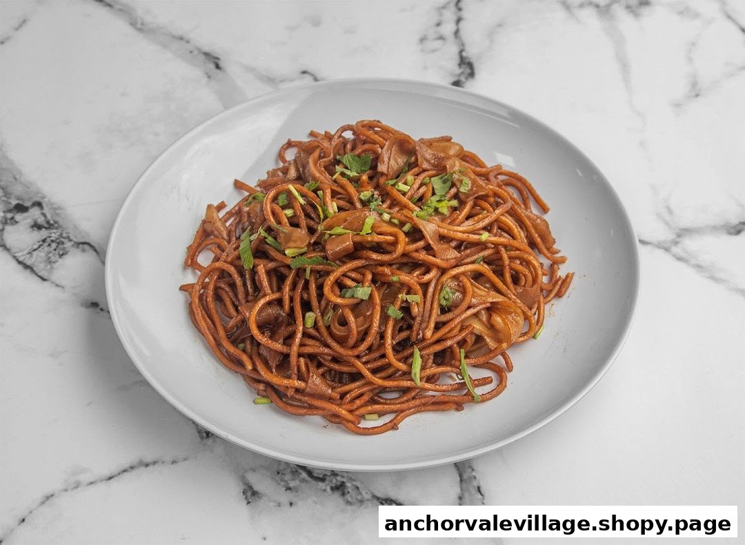 A plate of dark brown stir-fried noodles with green garnishes on a white marble background.