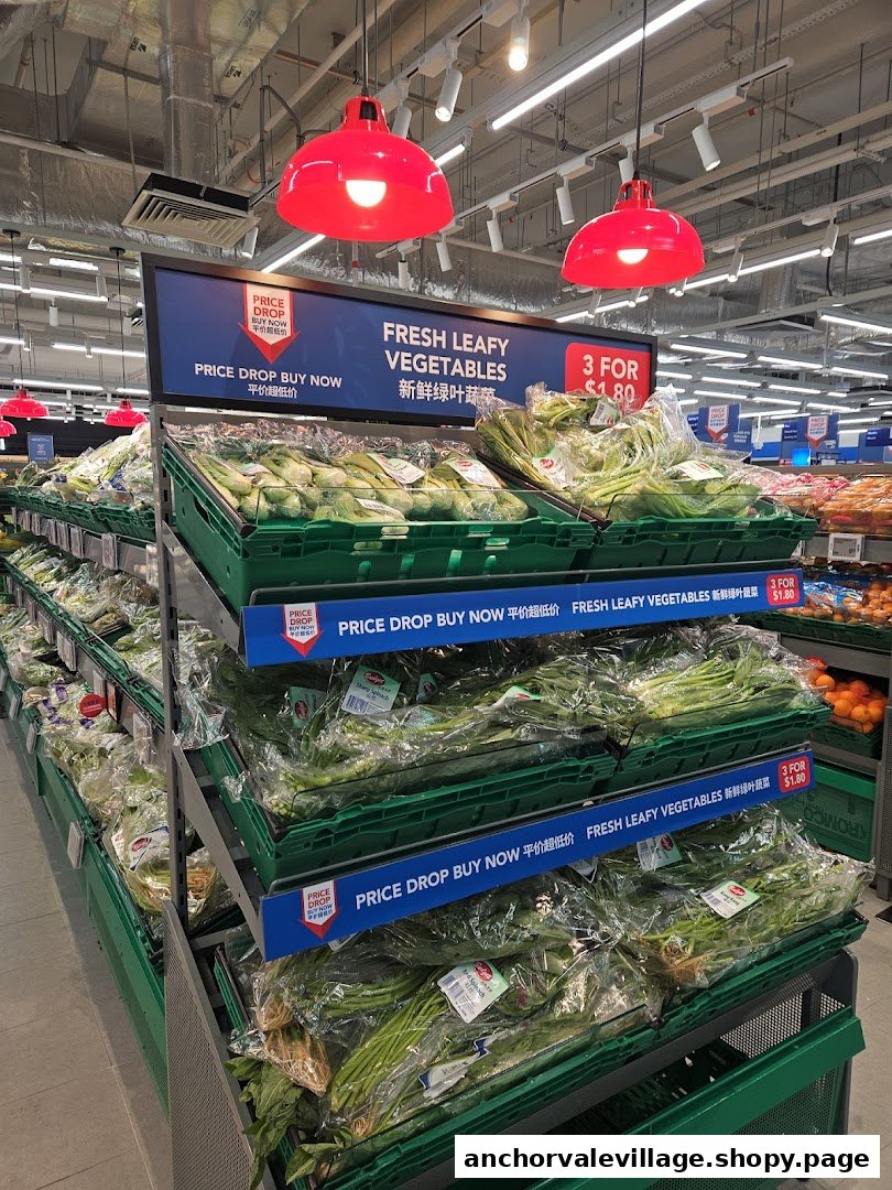 A supermarket aisle featuring a display of fresh leafy vegetables with 'Price Drop' promotions.