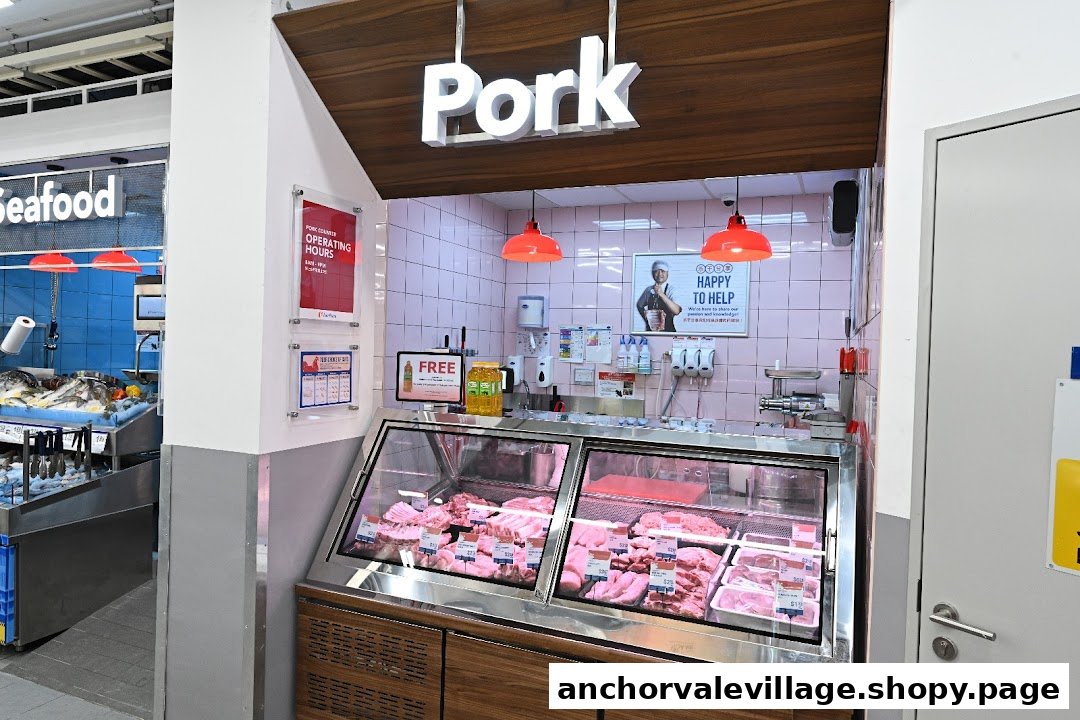 A well-stocked pork counter with various cuts of fresh meat displayed in a supermarket.