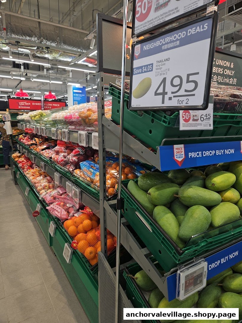 A supermarket aisle displaying fresh produce like mangoes and oranges, with prominent promotional signs.