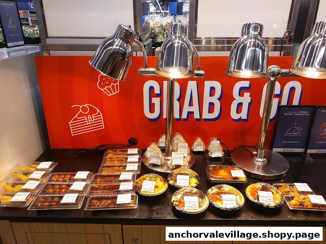 A FairPrice 'Grab & Go' counter displaying various pre-packaged hot meals and snacks under heat lamps.