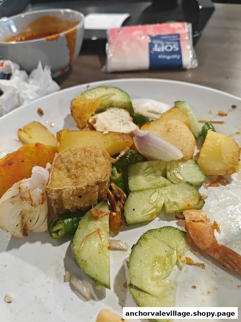 A close-up of a partially eaten plate of Rojak with cucumber, potatoes, tofu, and onions.