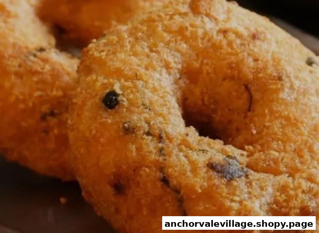A close-up of two golden-brown, crispy fried savory donuts, possibly Vada.