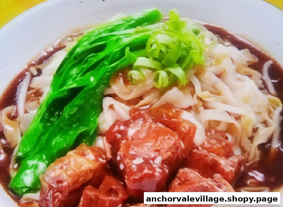A close-up of a delicious bowl of noodles with braised meat and fresh green vegetables.