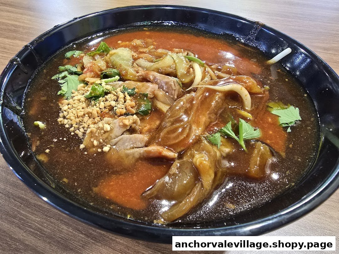 A close-up of a rich, savory beef noodle dish with vegetables and crushed peanuts.